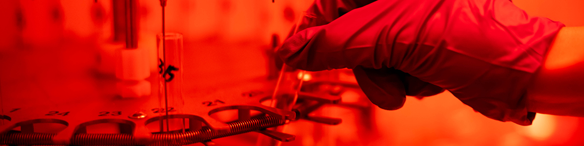 A gloved hand placing a test tube within a plate